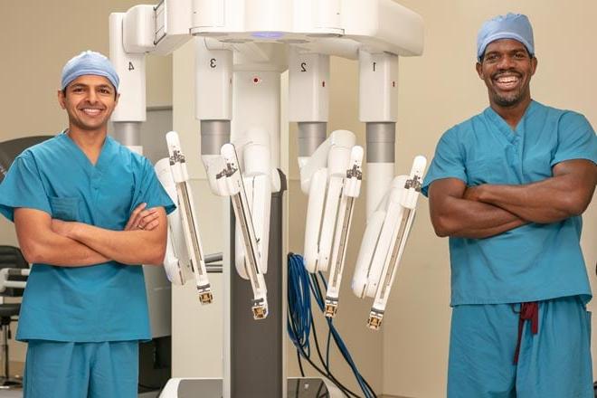 Two doctors standing next to robotic surgery equipment
